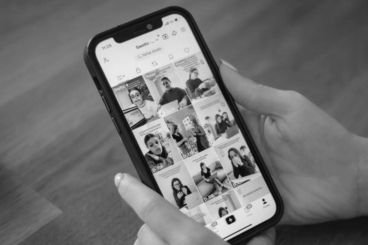 Mano sosteniendo un celular con un feed de fotos en pantalla